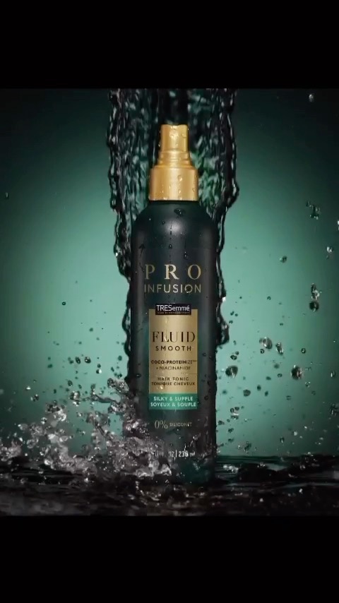 Tresemme Pro Infusion Fluid Smooth hair product bottle with water droplets against teal background in beauty and fashion setting.