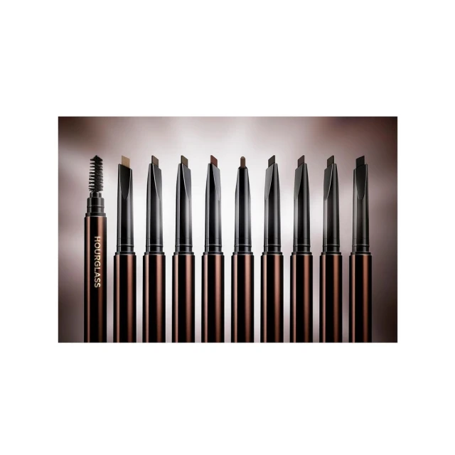 Hourglass brand collection of eyebrow pencils with various shades for beauty and cosmetics, arranged in a row against a gradient backdrop.