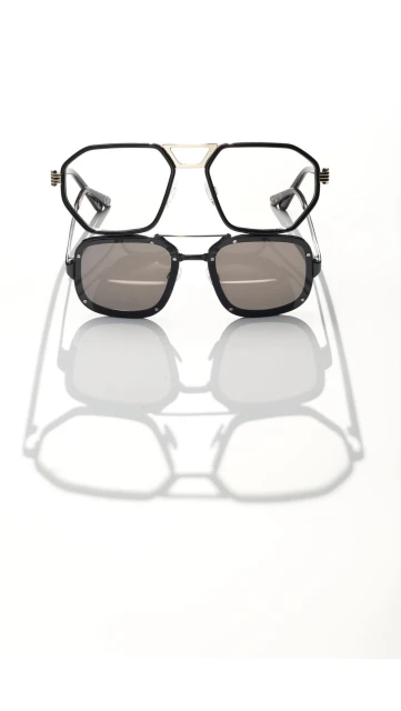 Studio shot of two pairs of stylish eyeglasses stacked, one with clear lenses and the other with sunglasses, casting strong shadows.