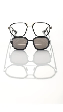 Studio shot of two pairs of stylish eyeglasses stacked, one with clear lenses and the other with sunglasses, casting strong shadows.