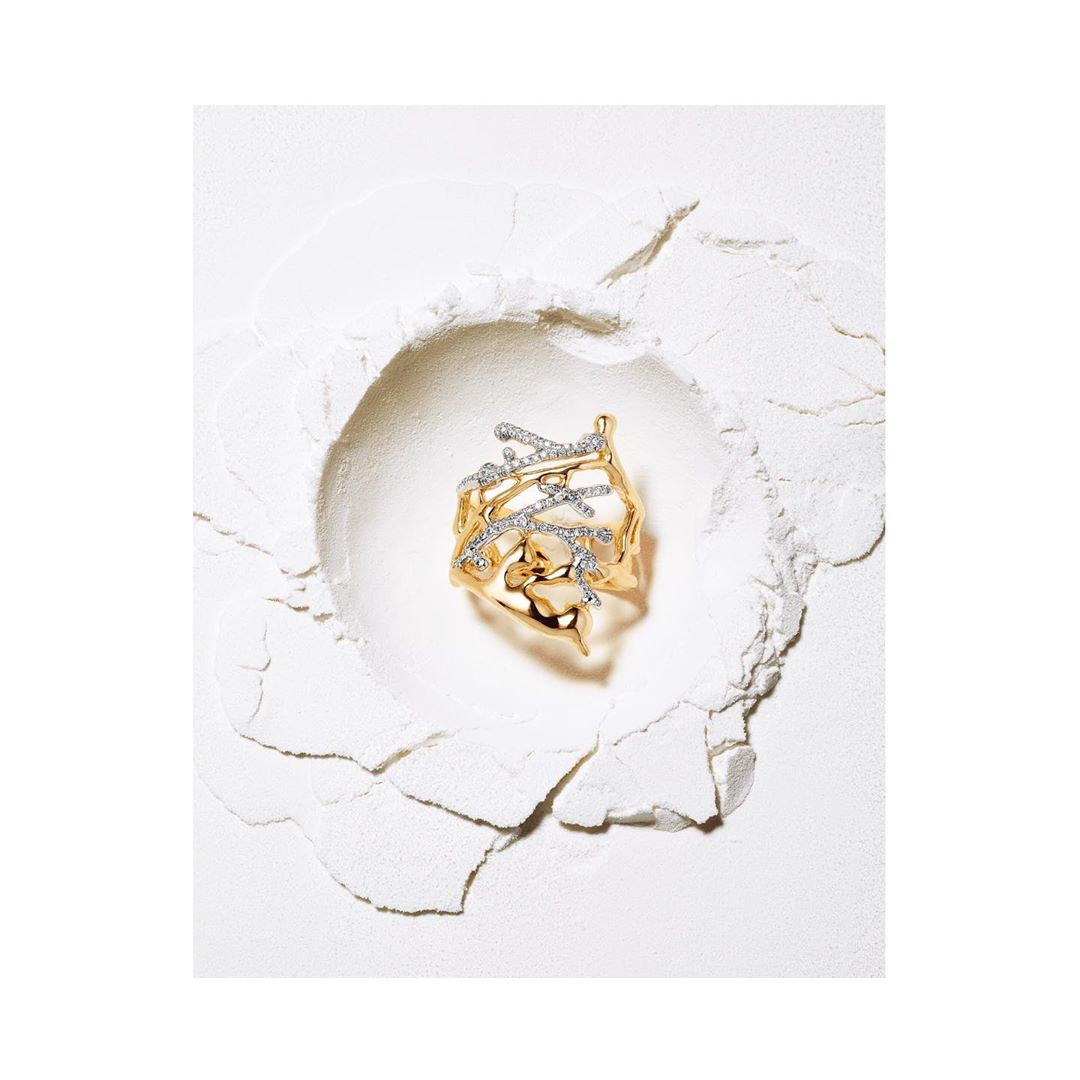 Elevated view of a gold ring featuring diamond accents, presented on a textured white surface, minimalist jewelry aesthetic.