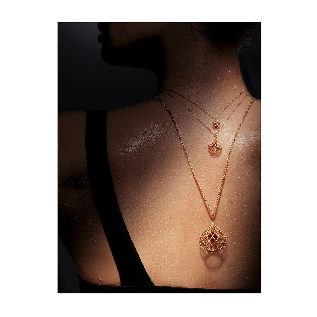 Back view of a woman wearing three gold necklaces against a dark background, emphasizing jewelry, fashion, and elegant design.
