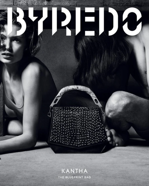 Byredo campaign features a black leather Kantha bag with white stitching between two models in a neutral setting, showcasing fashion and design.