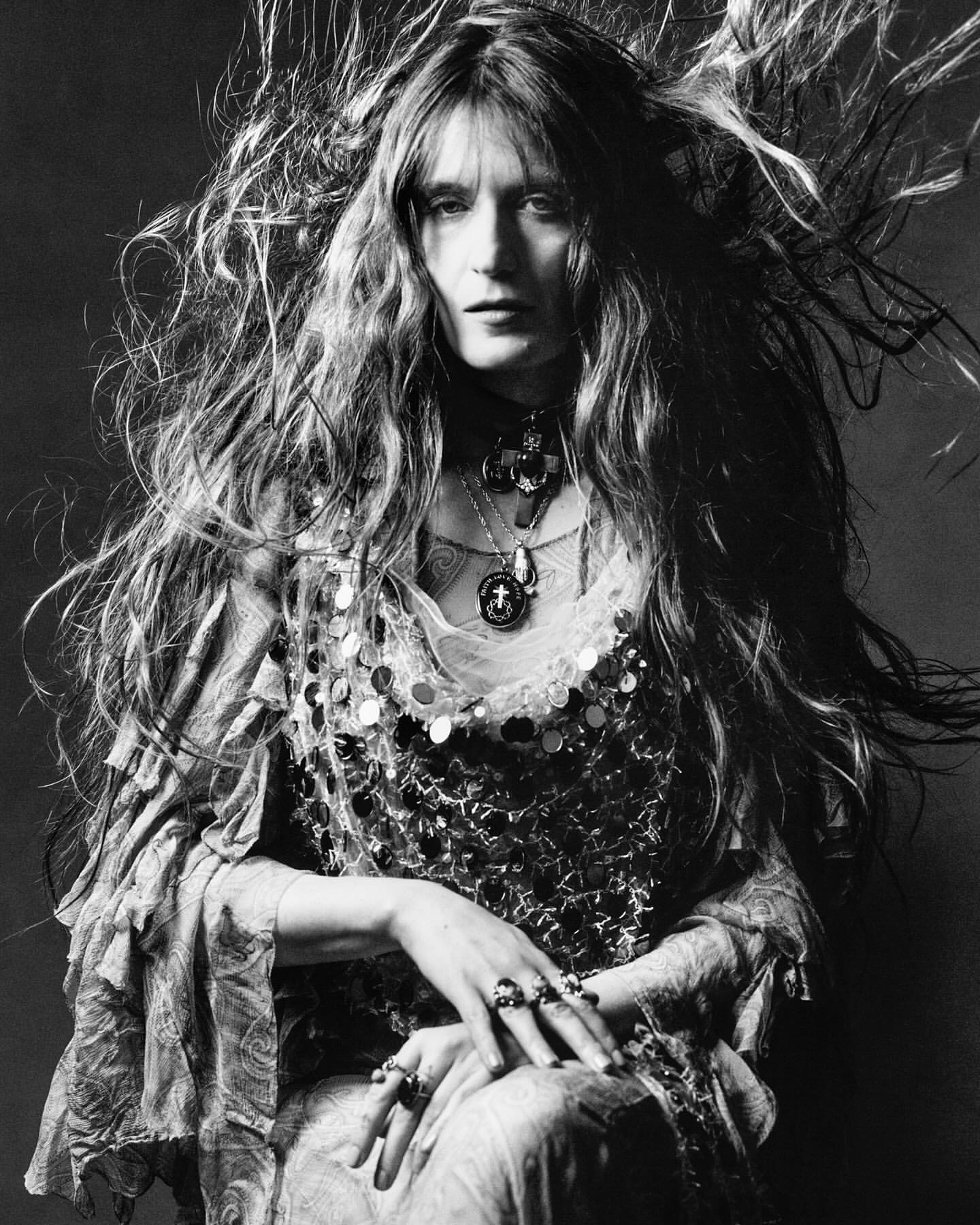 Monochrome portrait of a woman with long windblown hair wearing layered beaded necklaces and ornate rings photographed by Luis Alberto Rodriguez