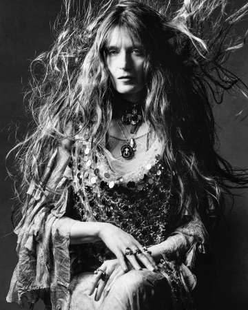 Monochrome portrait of a woman with long windblown hair wearing layered beaded necklaces and ornate rings photographed by Luis Alberto Rodriguez