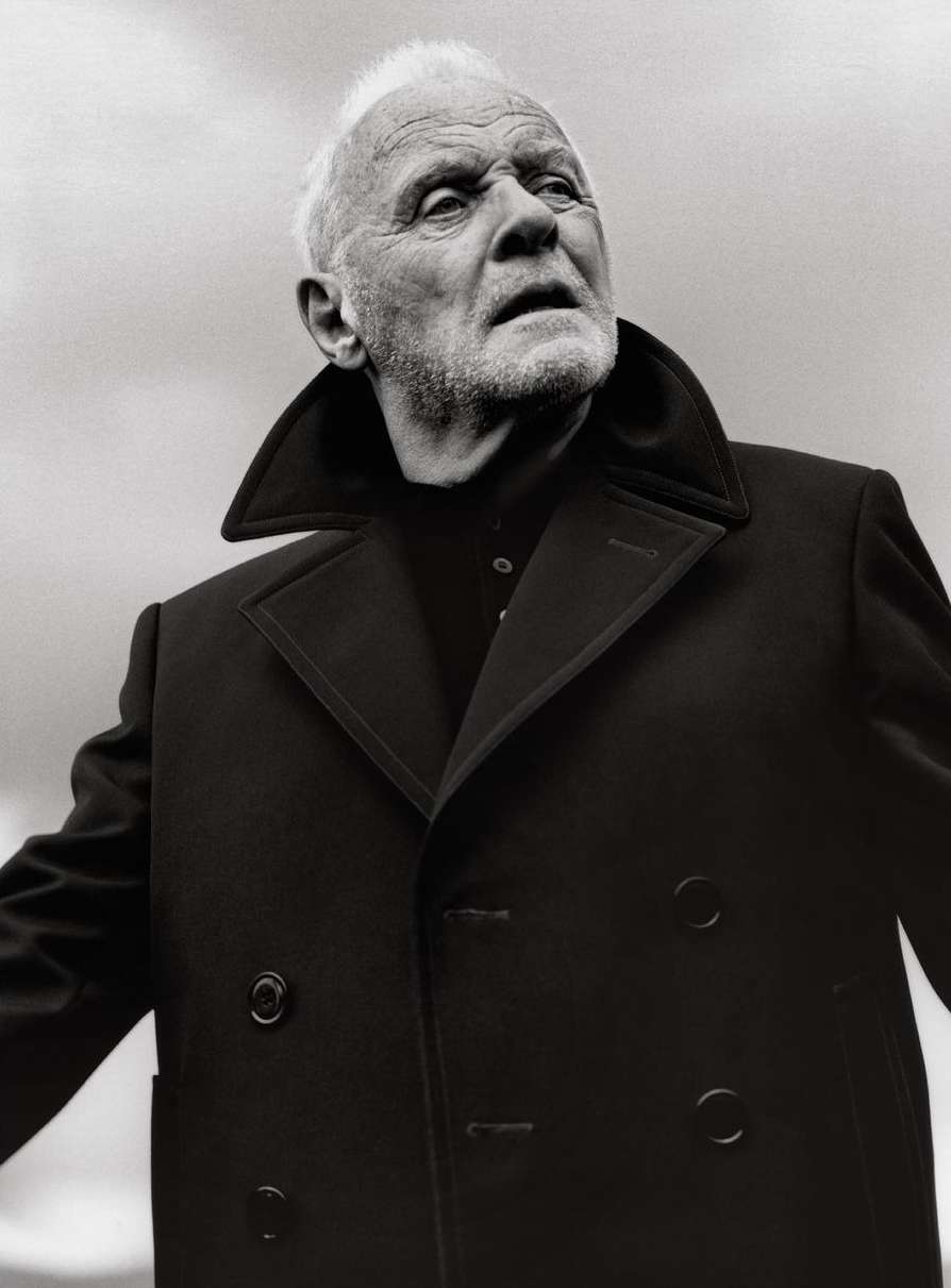 Black and white portrait of elderly adult male with light hair, wearing a dark coat, looking upward in an outdoor environment.