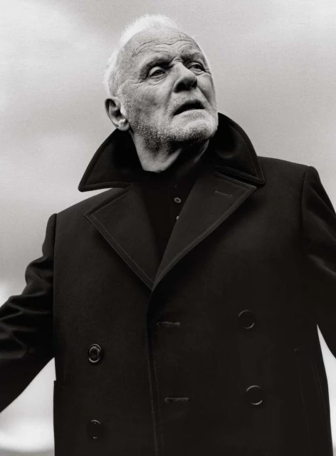 Black and white portrait of elderly adult male with light hair, wearing a dark coat, looking upward in an outdoor environment.