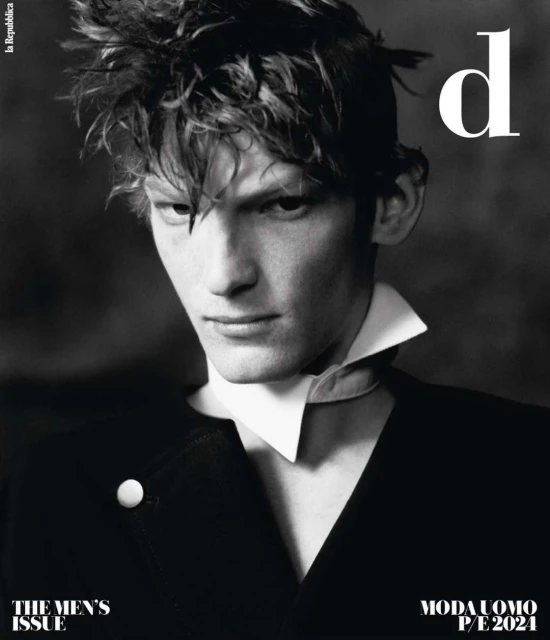 Black and white portrait of a male fashion model wearing a black suit and a white collared shirt for a magazine cover.