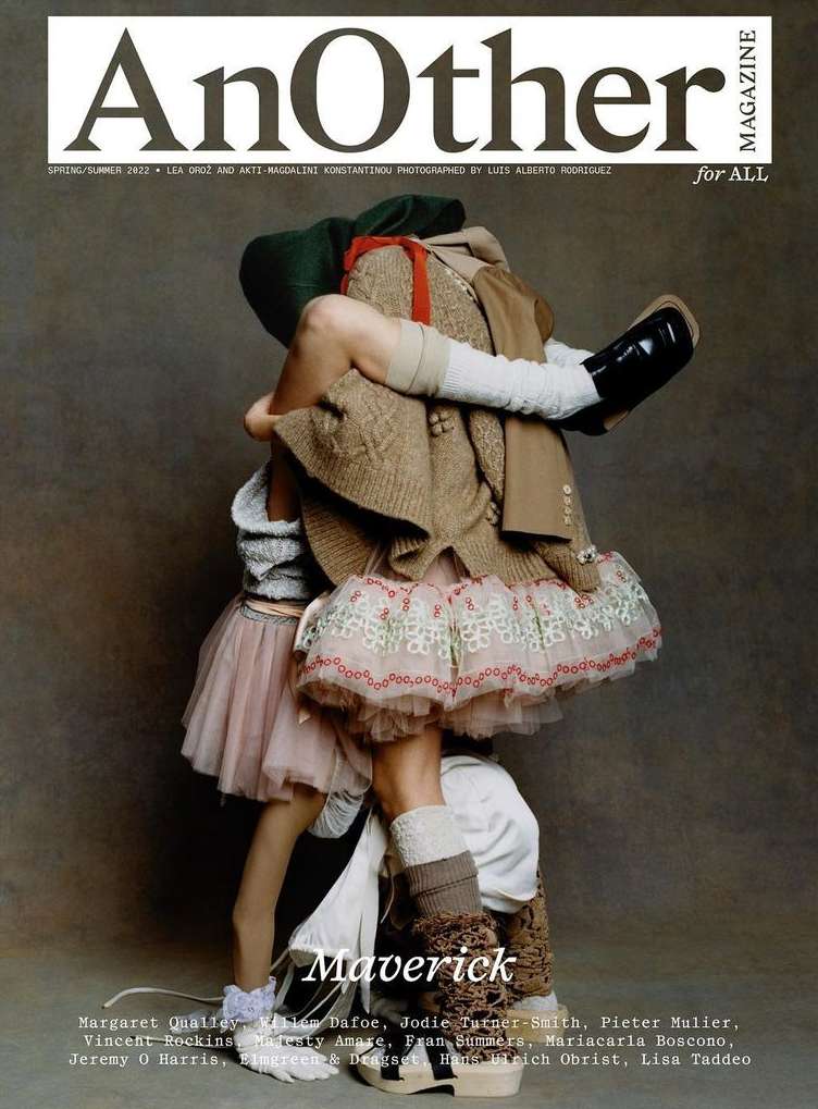 Fashion magazine cover featuring two figures in layers of textured clothing in an abstract, obscured embrace against a muted backdrop.