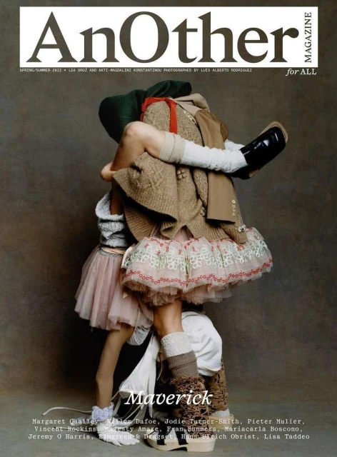 Fashion magazine cover featuring two figures in layers of textured clothing in an abstract, obscured embrace against a muted backdrop.