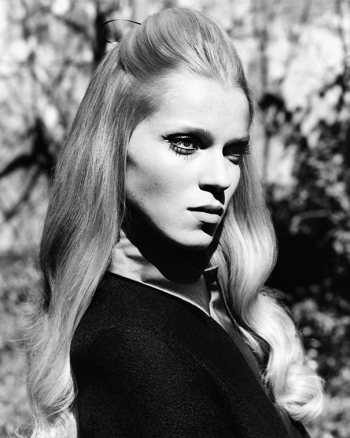 Portrait of a woman with voluminous blonde hair and dark eye makeup wearing a dark top, photographed by Luis Alberto Rodriguez.