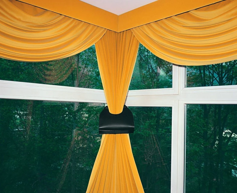 Interior view of a window with bright yellow curtains, creating a cozy and inviting atmosphere with natural light and outdoor view.