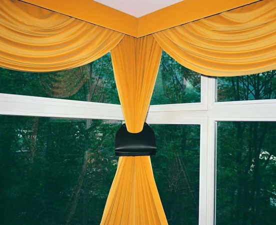 Interior view of a window with bright yellow curtains, creating a cozy and inviting atmosphere with natural light and outdoor view.