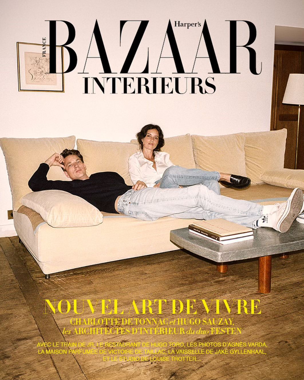 Harper's Bazaar Interiors magazine cover featuring a relaxed man and woman lounging on a beige sofa in an indoor setting with books.