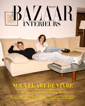 Harper's Bazaar Interiors magazine cover featuring a relaxed man and woman lounging on a beige sofa in an indoor setting with books.