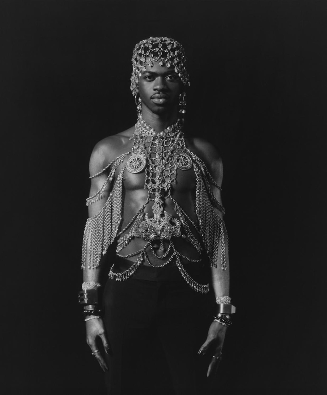 Striking portrait of a person with ornate jewelry, including a headdress and chains, against a dark background, fashion and style.
