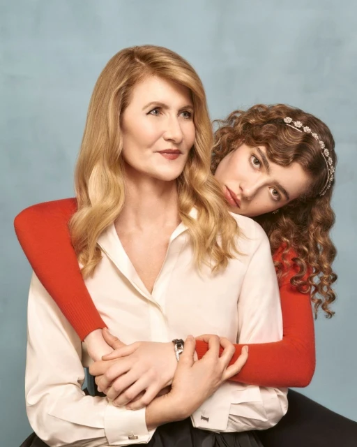 Indoor portrait of actress Laura Dern and a younger woman. The pair pose intimately in front of a simple light blue studio backdrop.