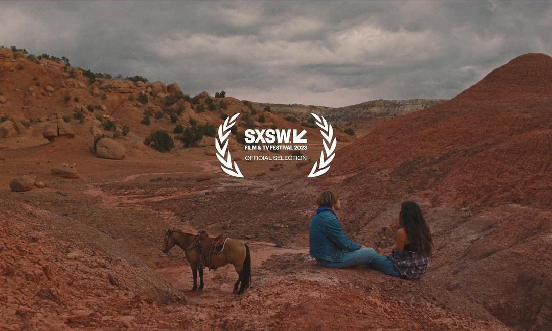 A couple sits in a desert landscape with a horse standing nearby, beneath the SXSW Film & TV Festival 2023 official selection logo.