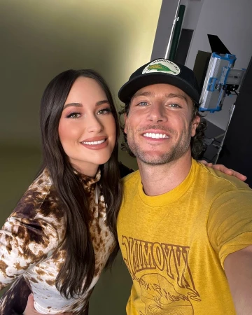 Headshot of an adult male and adult female smiling indoors with studio lighting and a light green background, portrait orientation.
