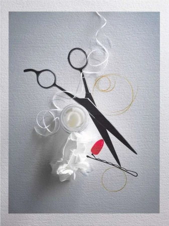 Hairdressing still life: black scissors, hair product, hair tie, bobby pin and tissue on a textured grey surface.