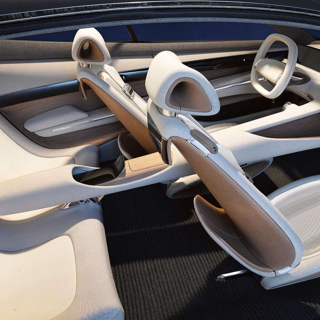 Car interior featuring white leather seats, wood trim, and a white steering wheel, showcasing modern automotive design and luxury.