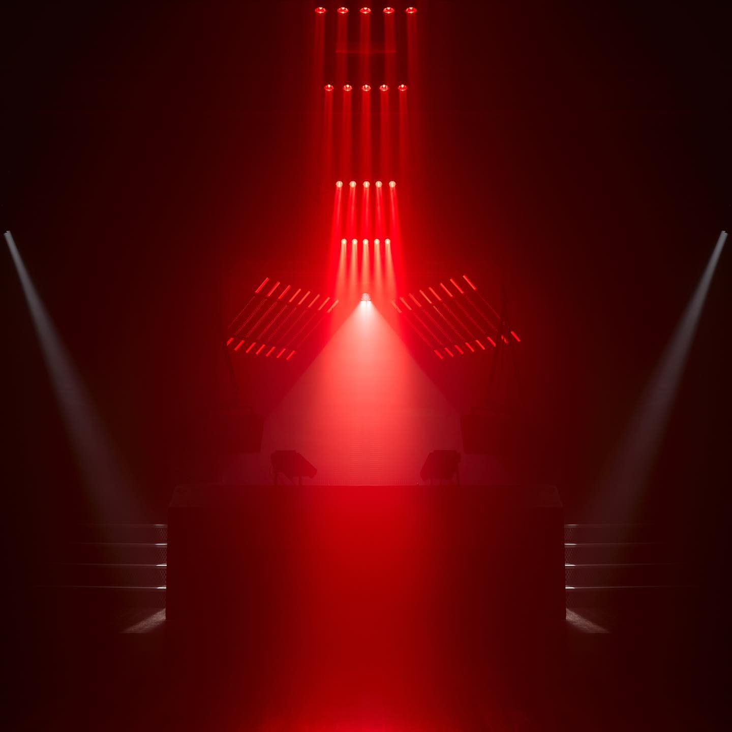 Stage with red lights shining on it, creating a dramatic and intense atmosphere for a performance or event, stairs on either side.