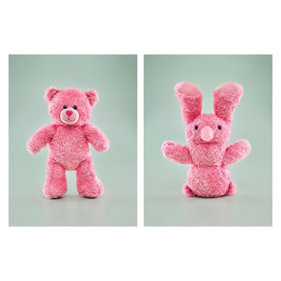 Pink stuffed teddy bear and bunny toy animals against a pale green background. Stuffed toys, children's toys, studio photography.