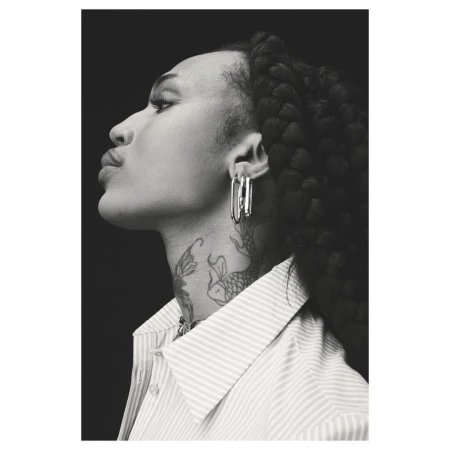 Black and white profile portrait of a woman wearing a striped shirt and large silver earrings with neck tattoos