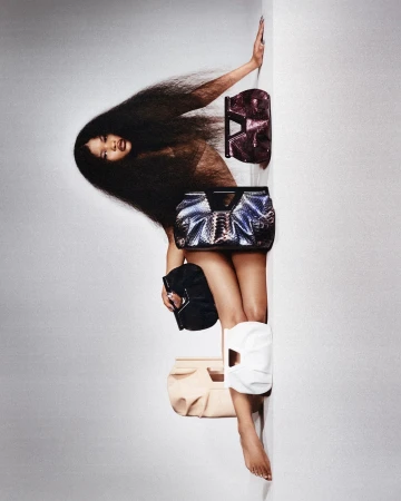 Model with long voluminous hair posing vertically with multiple handbags by photographer Lulu Mcardle