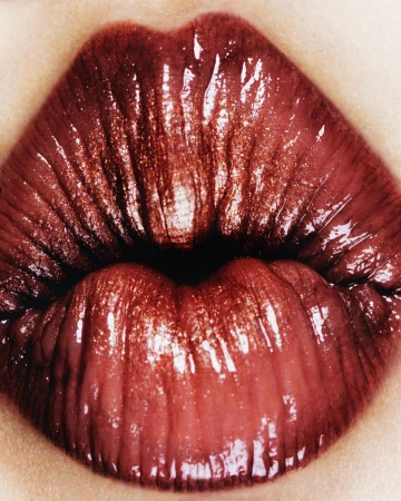 Extreme close-up of glossy dark red lips with visible texture, highlighting the makeup and skincare product focus on lip aesthetics.