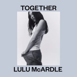 Black and white portrait of a woman wearing a white ribbed tank top holding denim trousers, photographed by Lulu McArdle