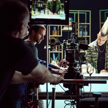A behind-the-scenes shot of a film or television production, featuring crew members and an actor with a mohawk at a bar setup.