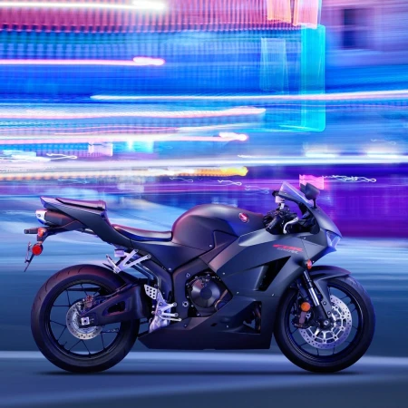 Black Honda CBR600RR motorcycle shown parked on a blue surface against an abstract background of neon blue, pink, and white light trails.
