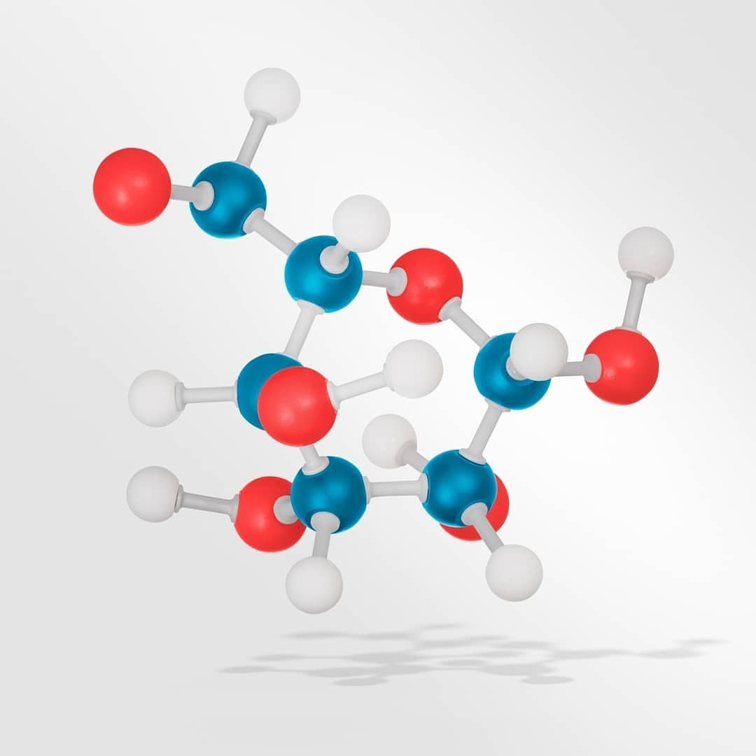 Molecular structure model with red, blue, and white spheres connected by rods, set against a light grey background with a subtle shadow.