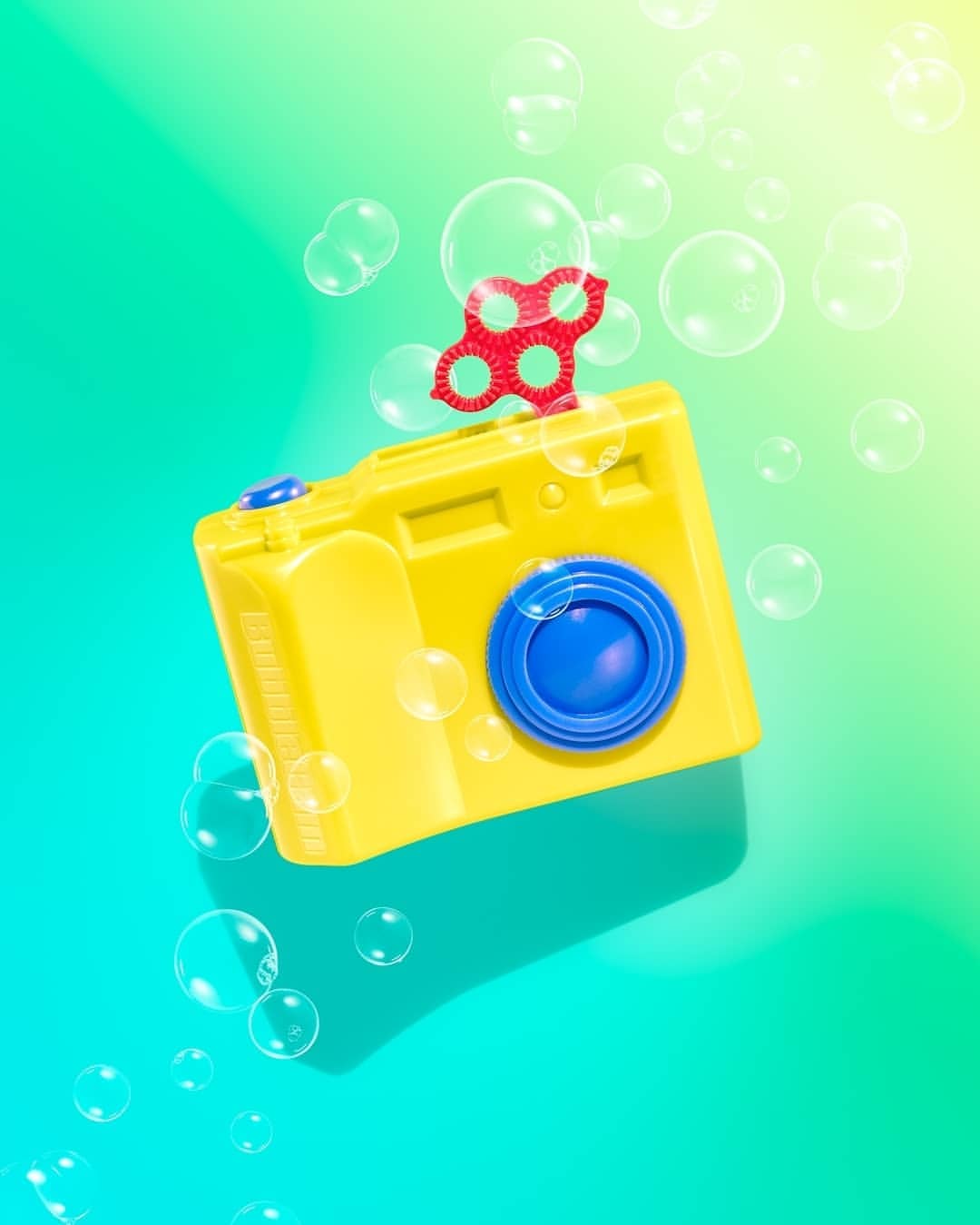 Whimsical yellow bubble blower camera on a vibrant green background surrounded by floating iridescent bubbles, creating a playful scene.