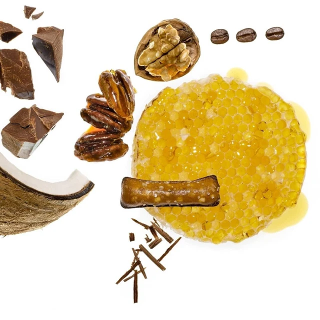 Overhead shot showcases honeycomb, chocolate chunks, coffee beans, walnuts, pecans, and coconut on a white background, studio lighting.