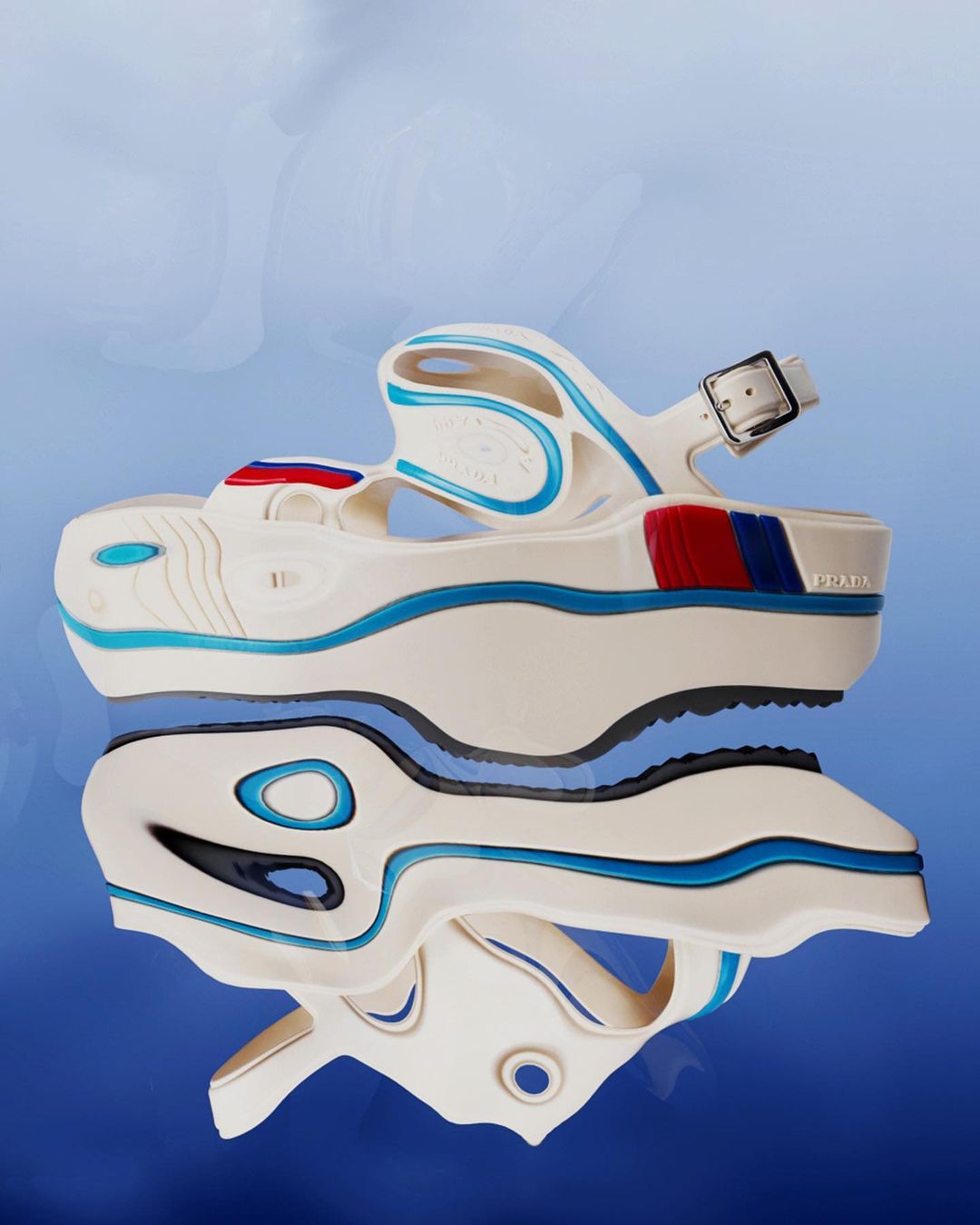 Elevated studio shot of a white platform sandal from Prada, reflected on a surface with light blue gradient backdrop; ideal for fashion content.