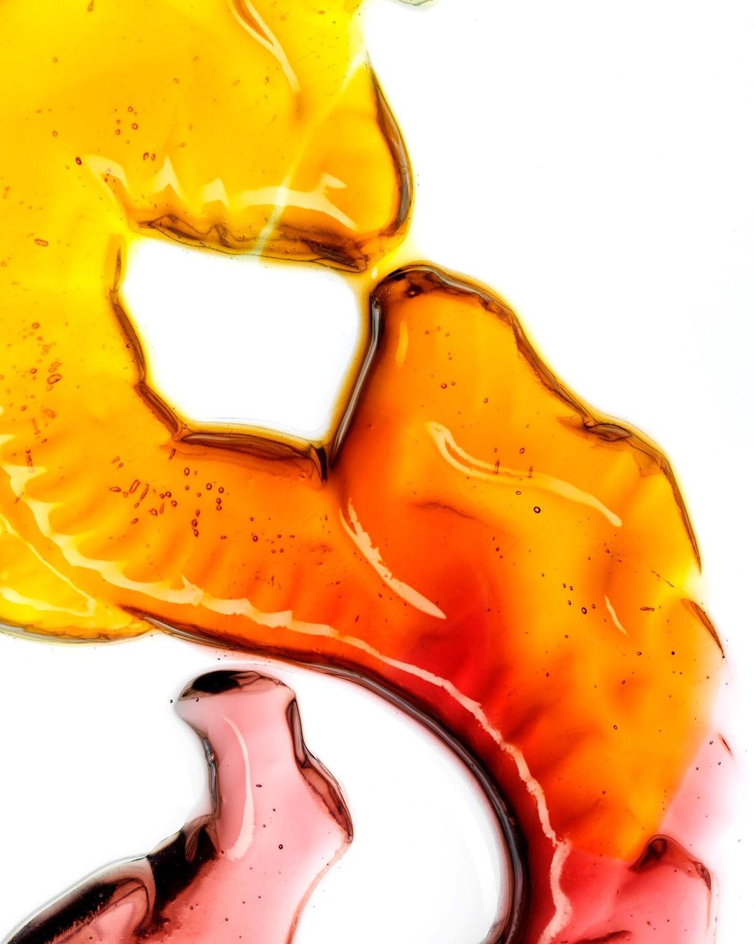 Abstract fluid art with translucent yellow, orange, and pink resin-like substances on a clean white backdrop. Modern organic art.