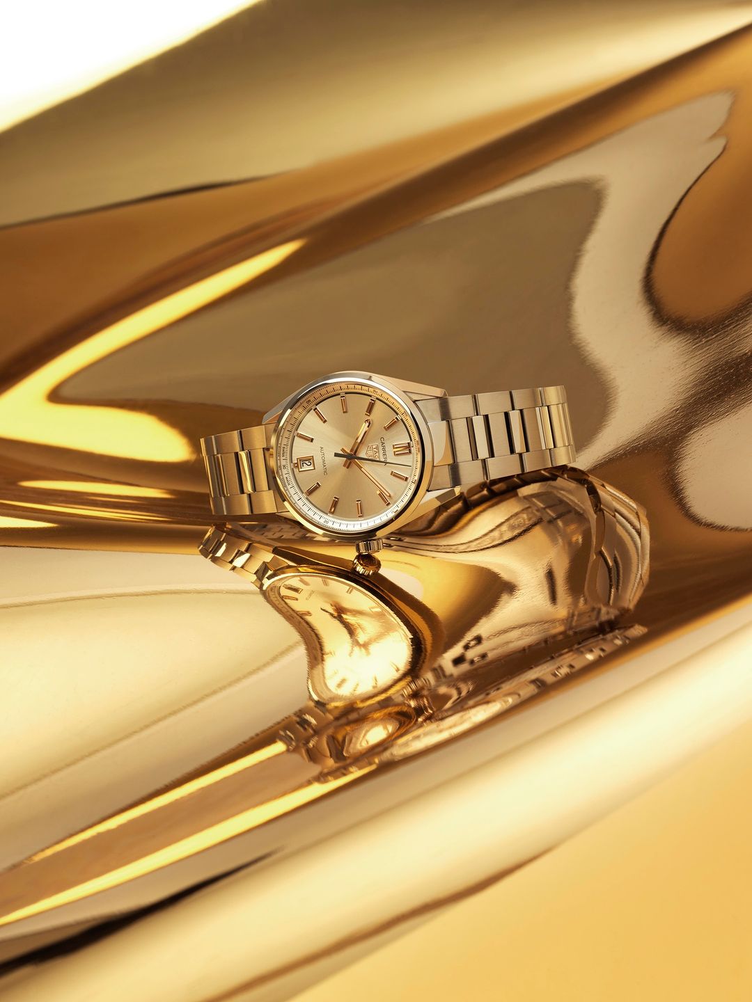 Close-up studio shot of an elegant gold wristwatch with a metal bracelet on a reflective gold surface, showcasing luxury timekeeping.