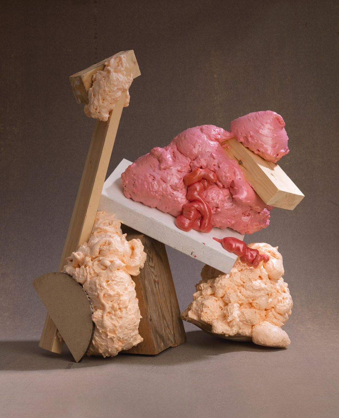 Abstract still life with pink and peach foam, wooden blocks, and geometric shapes creating a textured sculptural arrangement.