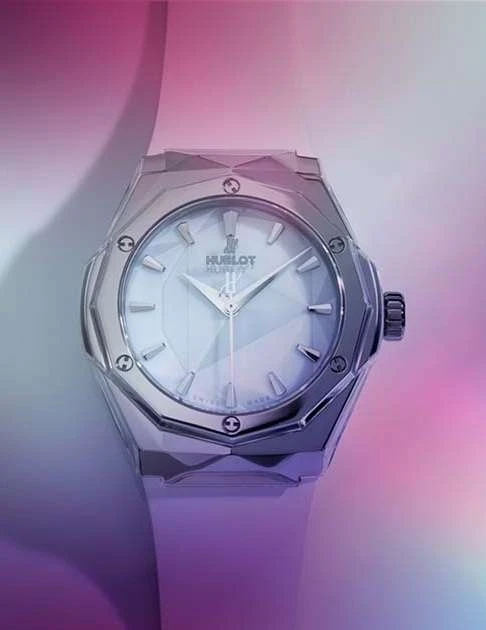 Close-up of a Hublot watch featuring a silver multifaceted design and mother-of-pearl dial against a soft, multi-colored backdrop.