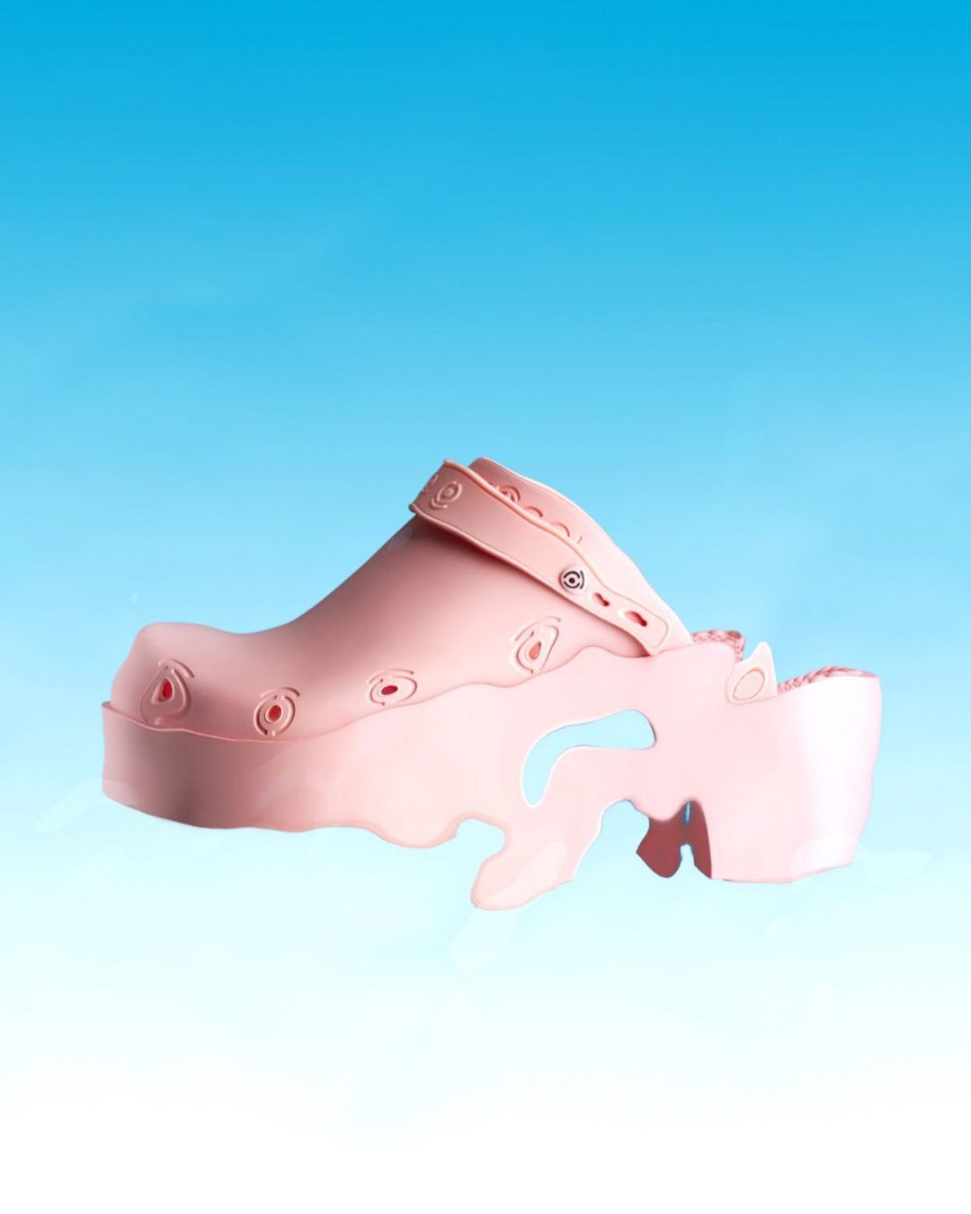 Elevated view of a single platform clog. The shoe is light pink and the background is a gradient of light blue and white.