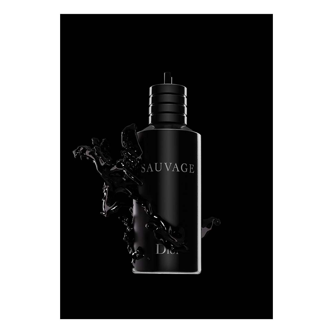 Close-up studio shot of a black Sauvage Dior cologne bottle surrounded by a dark liquid splash against a solid black backdrop.