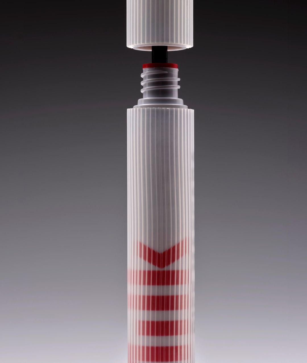 White marker with red writing stands against a gradient gray background, with the top open but the cap hovering just above.