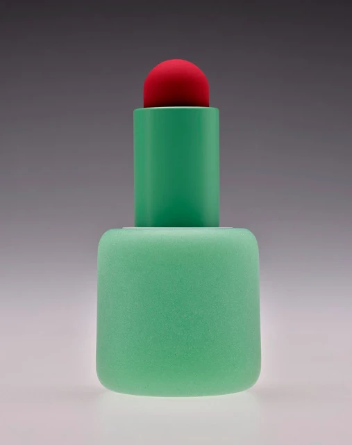 Minimalist studio shot of a geometric plastic sculpture in hues of green and red, set against a gradient gray background.