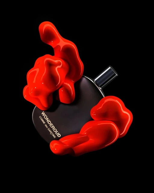 A black Comme des Garçons Wonderoud perfume bottle surrounded by bright orange paint-like blobs against a stark black background.