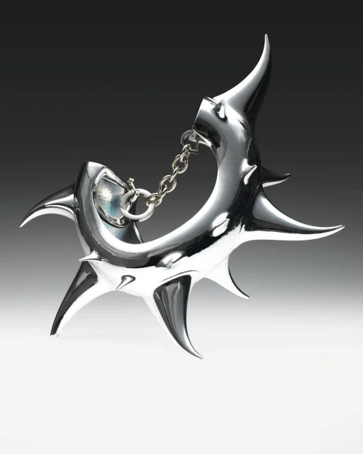 Close-up of a shiny, silver-colored abstract metal sculpture with pointed projections and a chain connection on a gradient background.