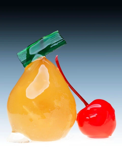 Close-up of a candied pear with a cherry alongside, featuring a glossy finish and set against a gradient blue background.
