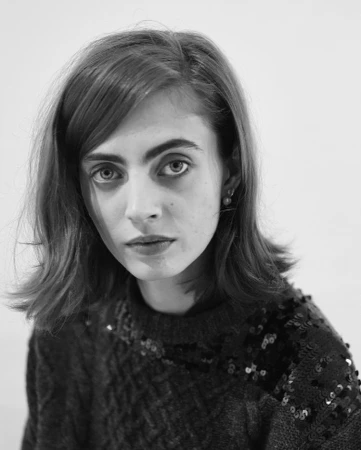 Monochrome portrait of a woman with shoulder-length dark hair wearing a sequined knit sweater against a plain background
