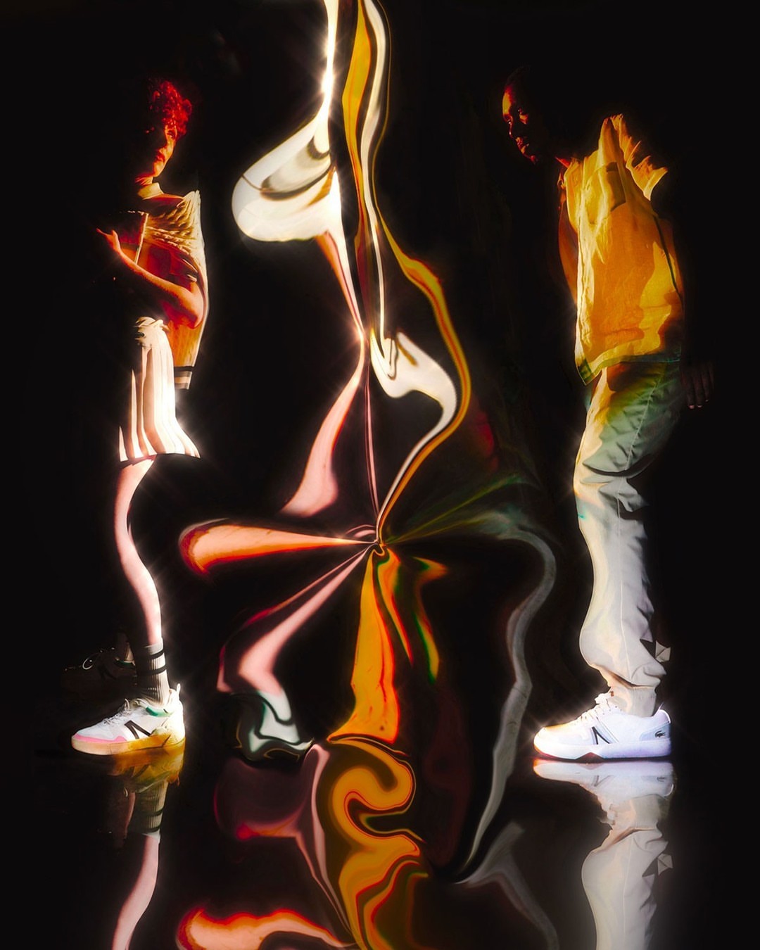 Two people stand in a dark space with a colorful swirling effect between them, showcasing a modern and artistic composition.